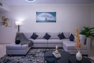 a living room with a couch and a tree at Luxury 2BR Haven with Panoramic Scenery - The Greens in Dubai