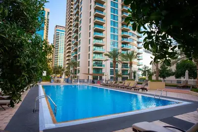 a swimming pool in front of a large building at Luxury 2BR Haven with Panoramic Scenery - The Greens in Dubai