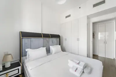 a white bedroom with a large bed with white pillows at Modern & Cozy 2BR Apartment at The Nook 1 Near Metro in Dubai