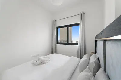 a white bedroom with a bed and a window at Modern & Cozy 2BR Apartment at The Nook 1 Near Metro in Dubai