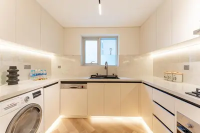 a white kitchen with a washer and dryer at HAVN- 3 bedroom in DAMAC Majestine, Business Bay in Dubai