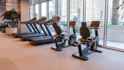 a row of treadmills in a gym with a large window at Elegant Suites 2BDR In Forte Downtown-32 in Dubai