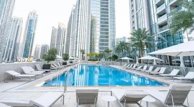 a swimming pool with chairs and a building at Elegant Suites 2BDR In Forte Downtown-32 in Dubai