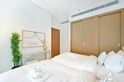 a bedroom with a large white bed and a desk at Bloomfields Grandeur 2BR in Azizi Riviera in Dubai