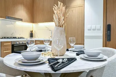 a table with plates and wine glasses on it in a kitchen at Bloomfields Grandeur 2BR in Azizi Riviera in Dubai