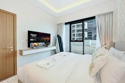 a bedroom with a white bed and a tv at Bloomfields Grandeur 2BR in Azizi Riviera in Dubai