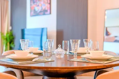 a wooden table with plates and glasses on it at TRPS - Burj Crown, Downtown - Skyline and Pool View, Furnished, Downtown in Dubai