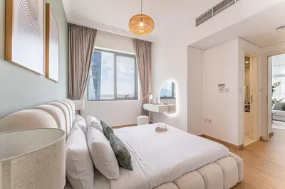 a white bedroom with a bed and a table at HAVN- High floor 1 bedroom in Business Bay in Dubai