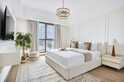 a white bedroom with a large bed and a window at Frank Porter - Al Jazi in Dubai