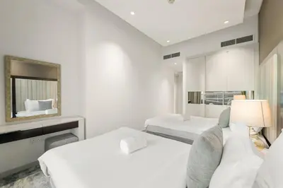 a white bedroom with two beds and a mirror at FIRST CLASS 2BR Vibrant Next to Dubai Mall in Dubai