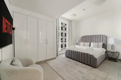 a white bedroom with a bed and a chair at VayK - Stylish 2BD in Dubai Marina Near the Beach in Dubai