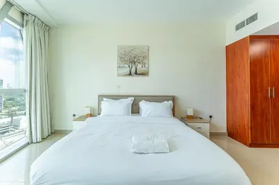 a bedroom with a large white bed and a window at HAVN - 3 bedroom in Park Towers, DIFC in Dubai