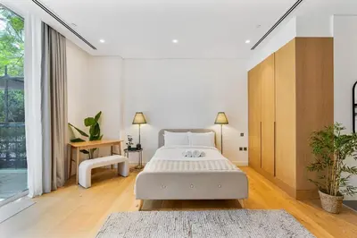 a white bedroom with a bed and a large window at Serene Studio in Al Barari Near Dubai Hills Mall in Dubai