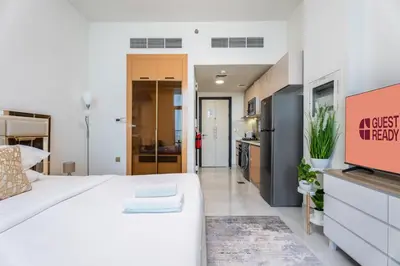 a bedroom with a large white bed and a kitchen at GuestReady - Studio Suite l Community Jacuzzi in Dubai