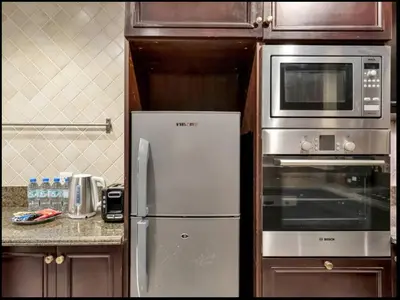 a kitchen with a refrigerator and a microwave at Skyline Souk 1 & 2 Bedroom Apartments I Burj Khalifa Views I Private Terrace I Gym, Pool, Parking & Wi-Fi in Dubai