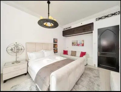 a white bedroom with a large bed and a couch at Skyline Souk 1 & 2 Bedroom Apartments I Burj Khalifa Views I Private Terrace I Gym, Pool, Parking & Wi-Fi in Dubai