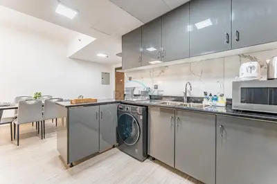 a kitchen with a washing machine and a sink at Compact 1BR, Just A Minute Drive to At the Top Burj Khalifa - Ontario Tower, Business Bay in Dubai