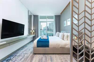 a bedroom with a large bed and a flat screen tv at PVH - Damac Maison Prive - Studio with Canal and Pool View in Dubai