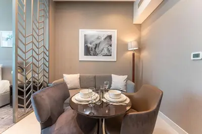 a dining room with a table and chairs and a couch at PVH - Damac Maison Prive - Studio with Canal and Pool View in Dubai