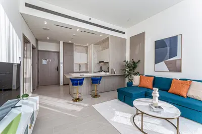 a living room with a blue couch and a kitchen at HAVN - High floor 1BR with Private Sky Pool, JVC in Dubai