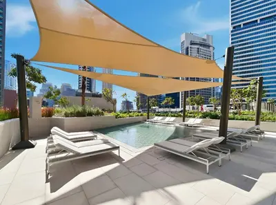 a swimming pool with lounge chairs and a large umbrella at Stylish 1BR Apartment Peninsula One Business Bay in Dubai