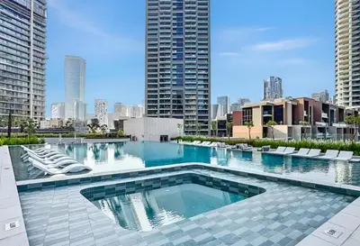 a large swimming pool with lounge chairs and buildings at Stylish 1BR Apartment Peninsula One Business Bay in Dubai