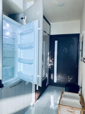 a kitchen with white cabinets and a glass refrigerator at Chic Studio near Miracle Garden & GlobalVillage in Dubai