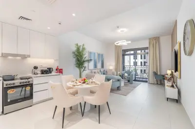 a kitchen and living room with a table and chairs at Vogue Madinat Jumeirah Living Jadeel near Burj AlArab, One-Bedroom Apartment with Large Balcony and Pool View, Access to All Amenities in Dubai