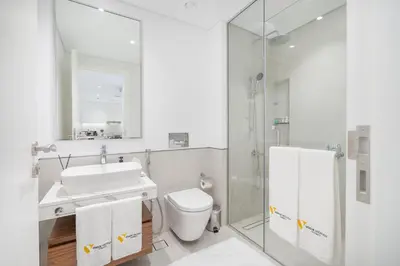 a bathroom with a sink and a toilet and a mirror at Vogue Madinat Jumeirah Living Jadeel near Burj AlArab, One-Bedroom Apartment with Large Balcony and Pool View, Access to All Amenities in Dubai