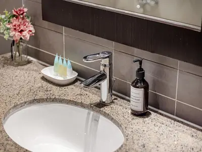 a bathroom sink with a bottle of soap and a mirror at Livin' Holidays - 2 BR - Anantara Beach View in Dubai