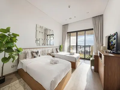a hotel room with two beds and a television at Livin' Holidays - 2 BR - Anantara Beach View in Dubai