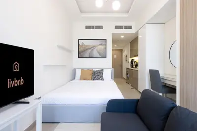 a bedroom with a bed and a tv and a couch at Bright Studio with Balcony Close to Downtown Dubai in Dubai
