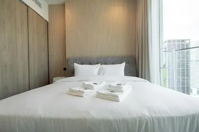 a white bed with two folded towels on it at Mystic - Luxe 1BR Apt with Burj Khalifa & Canal Views in Dubai