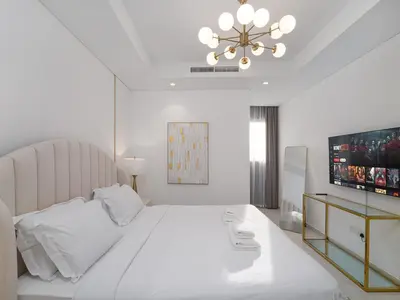 a white bedroom with a large bed and a television at Luxury 1BR High floor Paramount Midtown in Dubai