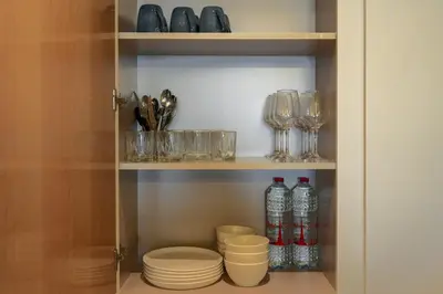 a cupboard with plates and glasses and wine bottles at BurjKhalifaViews,1BHK, High Floor, Damac Paramount Tower B in Dubai