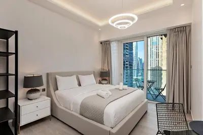 a white bedroom with a large bed and a balcony at Chic Studio in Me Do Re JLT YOLO in Dubai