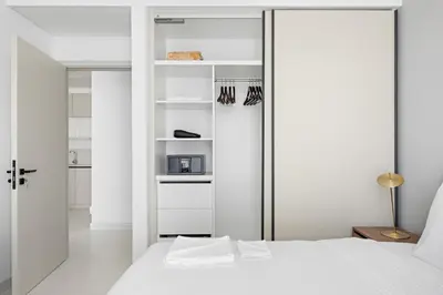 a white bedroom with a bed and a closet at Silkhaus 1BDR in Marina Vista Tower Private Beach in Dubai