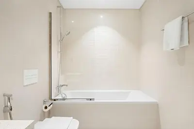 a white bathroom with a tub and a toilet at Silkhaus 1BDR in Marina Vista Tower Private Beach in Dubai