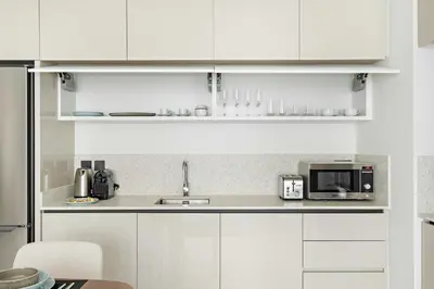 a white kitchen with a sink and a microwave at Silkhaus 1BDR in Marina Vista Tower Private Beach in Dubai