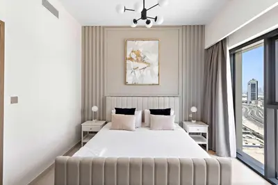 a white bedroom with a large bed and a window at Silkhaus Prime 1BDR in Burj Royale in Dubai
