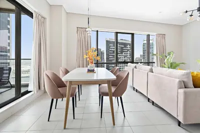 a living room with a table and chairs and a couch at Silkhaus 1 BDR in South Ridge on High Floor in Dubai