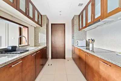 a large kitchen with wooden cabinets and a sink at Silkhaus 1 BDR in South Ridge on High Floor in Dubai