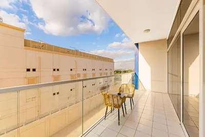 a balcony with two chairs and a table on a building at Escape 24 Stylish 1BR in Artesia, Pool & Gym, Damac Hills in Dubai