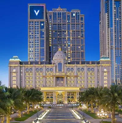 a building with palm trees in front of tall buildings at Al Habtoor Palace - Preferred Hotels & Resorts in Dubai