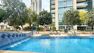 a swimming pool with chairs in front of a building at Vogue Downtown Burj Residence Near Dubai Mall and Burj Khalifa, Three Bedroom Plus Maid's room Apartment with Balcony and City View, Access to all Amenities in Dubai