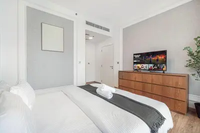 a white bedroom with a large bed and a flat screen tv at Palm Jumeirah Luxury Direct Beach Access and Views in Dubai