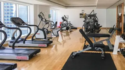 a gym with several treadmills and elliptical machines at Stylish 1BR close to Metro and Dubai Marina in Dubai