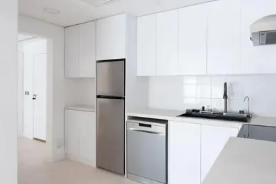 a kitchen with white cabinets and a stainless steel refrigerator at Modern & Bright 2 Bedroom Apartment at The Palm in Dubai