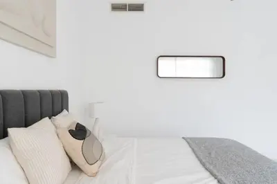 a bedroom with white walls and a bed with white pillows at Modern & Bright 2 Bedroom Apartment at The Palm in Dubai
