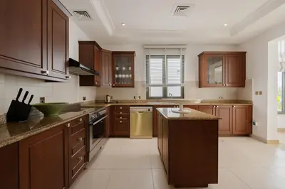 a large kitchen with wooden cabinets and appliances at Maison Privee - Villa on Beach with Private Pool The Palm Jumeirah in Dubai